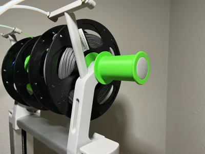 Four black filament spools on the printer spool holder, the green sleeve on the front tube