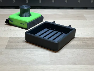 The empty black holder on the workbench, the green cleaner behind it