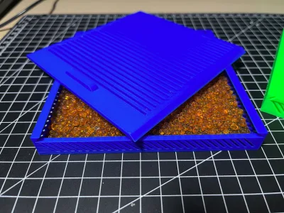 The blue box with the lid lifted off, the compartment filled with orange silica gel beads